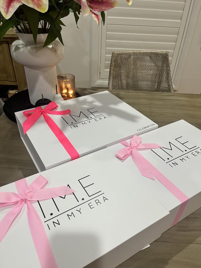 I.M.E gift boxes finished with pink ribbons and arranged beside flowers