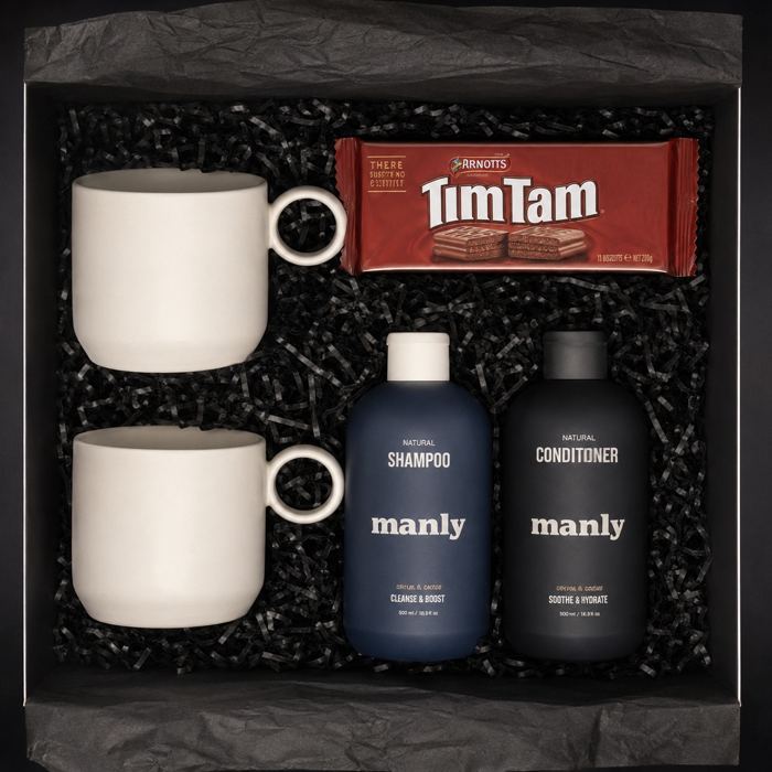 Gift box with two white mugs, biscuits, and shampoo and conditioner